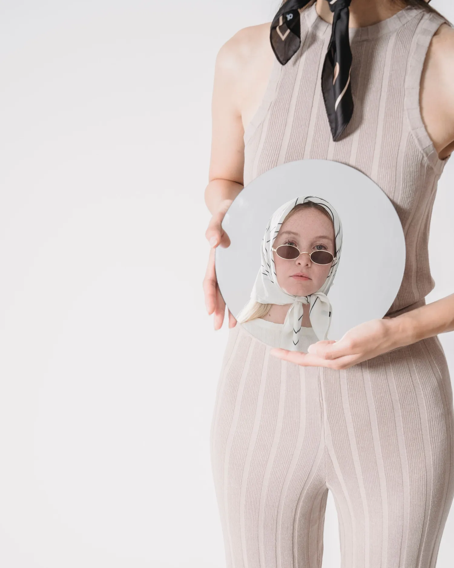 Rib Vest — Clay ribbed knit set worn with a silk square, holding a round mirror