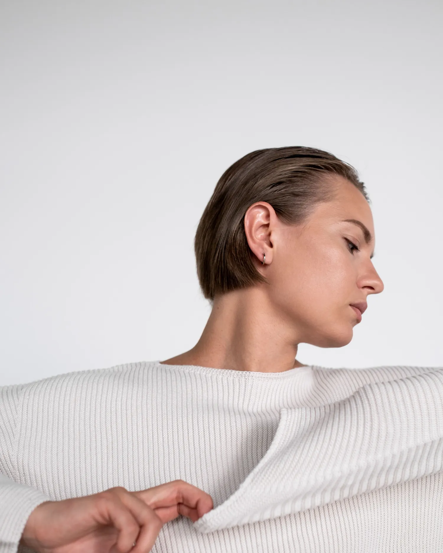 Still Crewneck — Model in an undyed lambswool crewneck sweater against a white ground