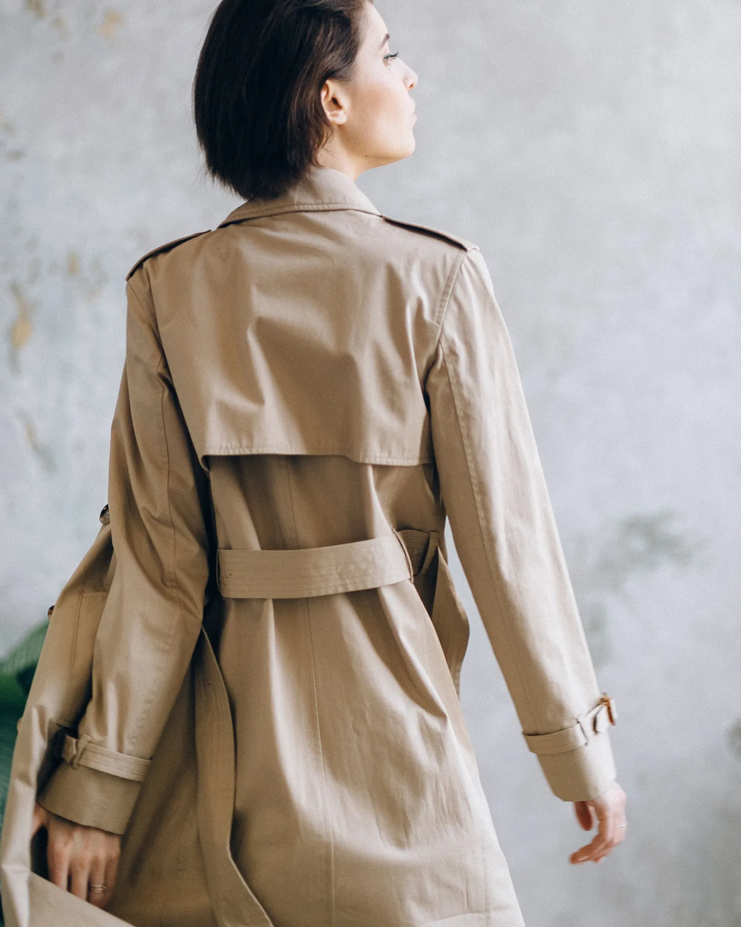 Back view of a sand linen long coat showing the storm yoke and belt