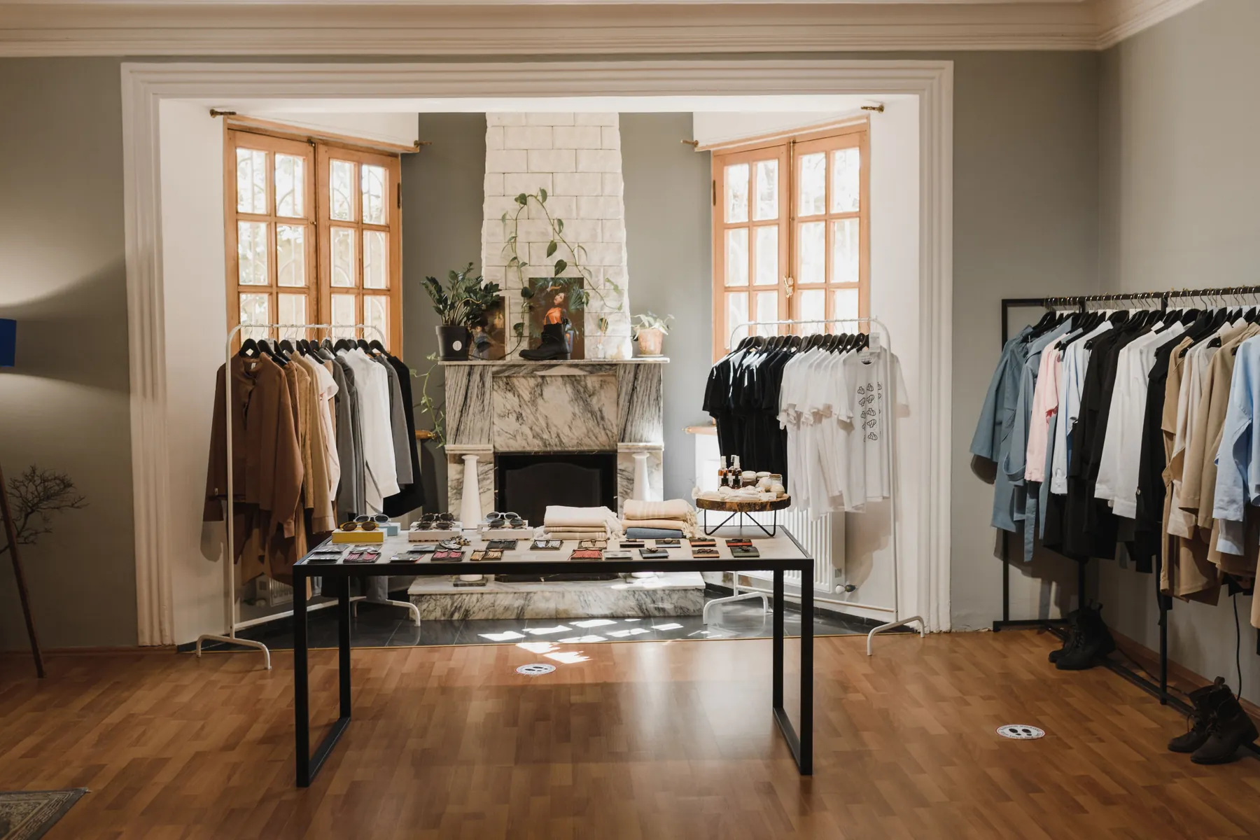 A bright boutique interior with a rail of neutral garments and a marble fireplace